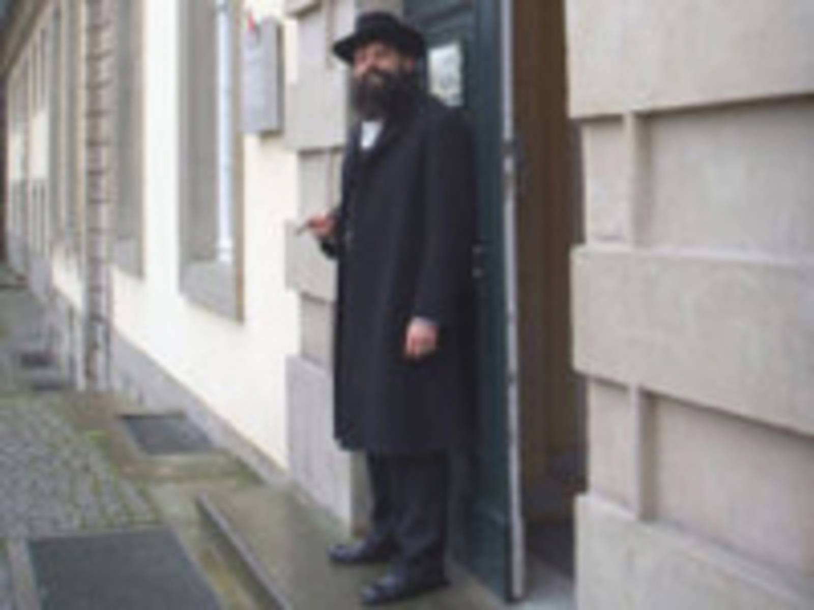 Ein Mann mit Bart steht vor einer Tür.