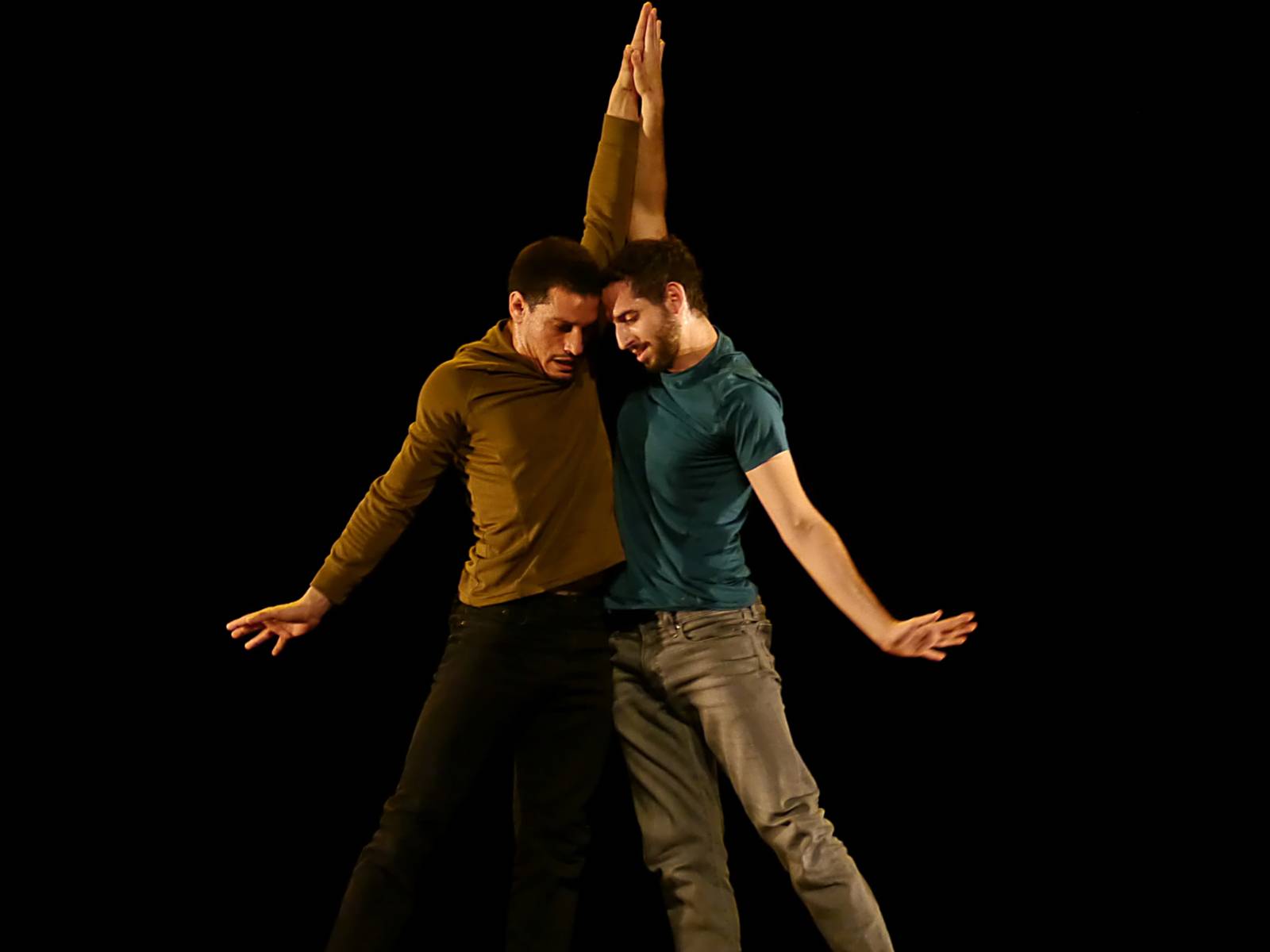 Zwei Männer auf einer Bühne, die sich an den Händen halten. 