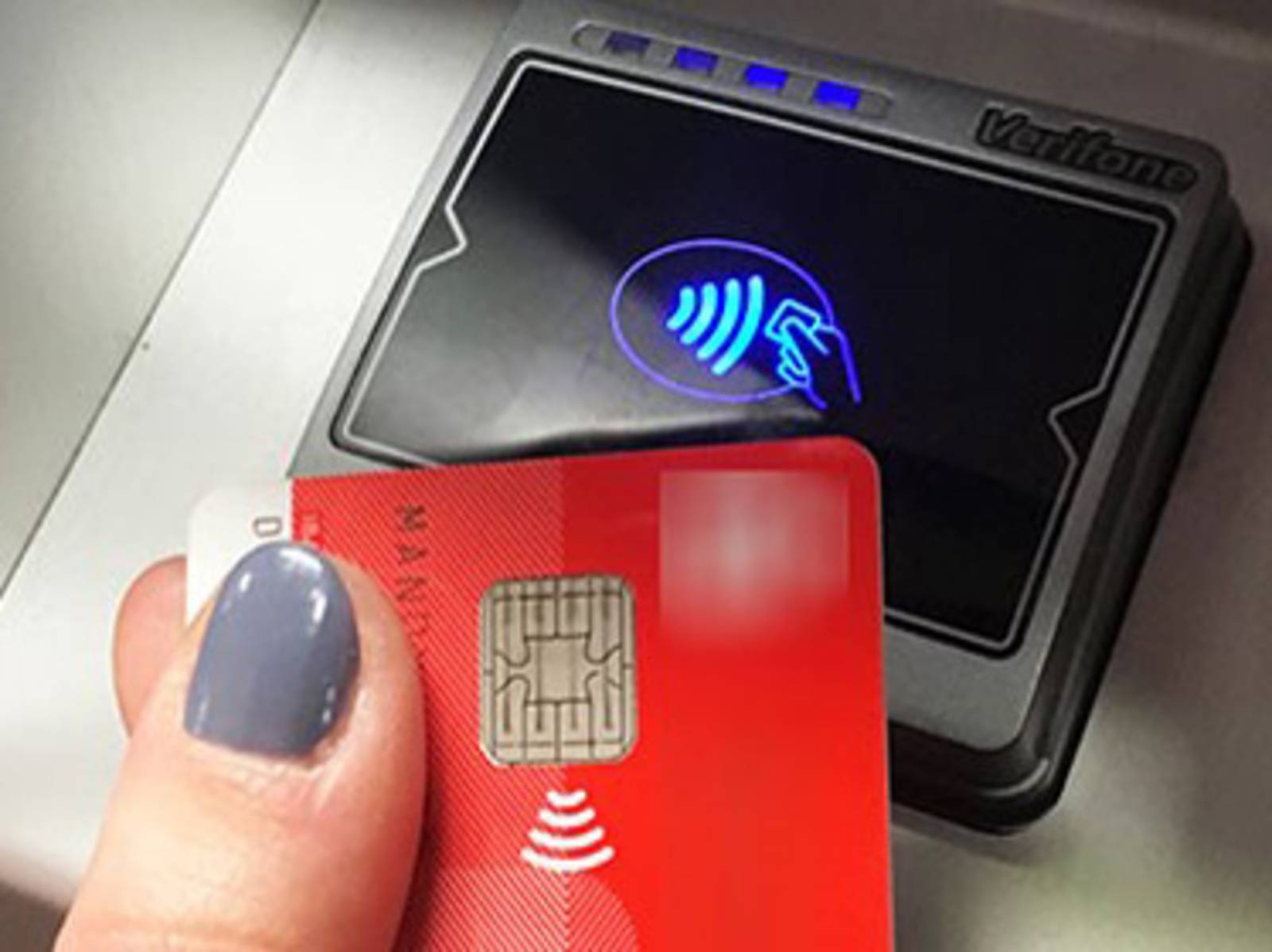 Hand hält eine EC-Karte vor ein Lesegerät zur kontaktlosen Zahlung