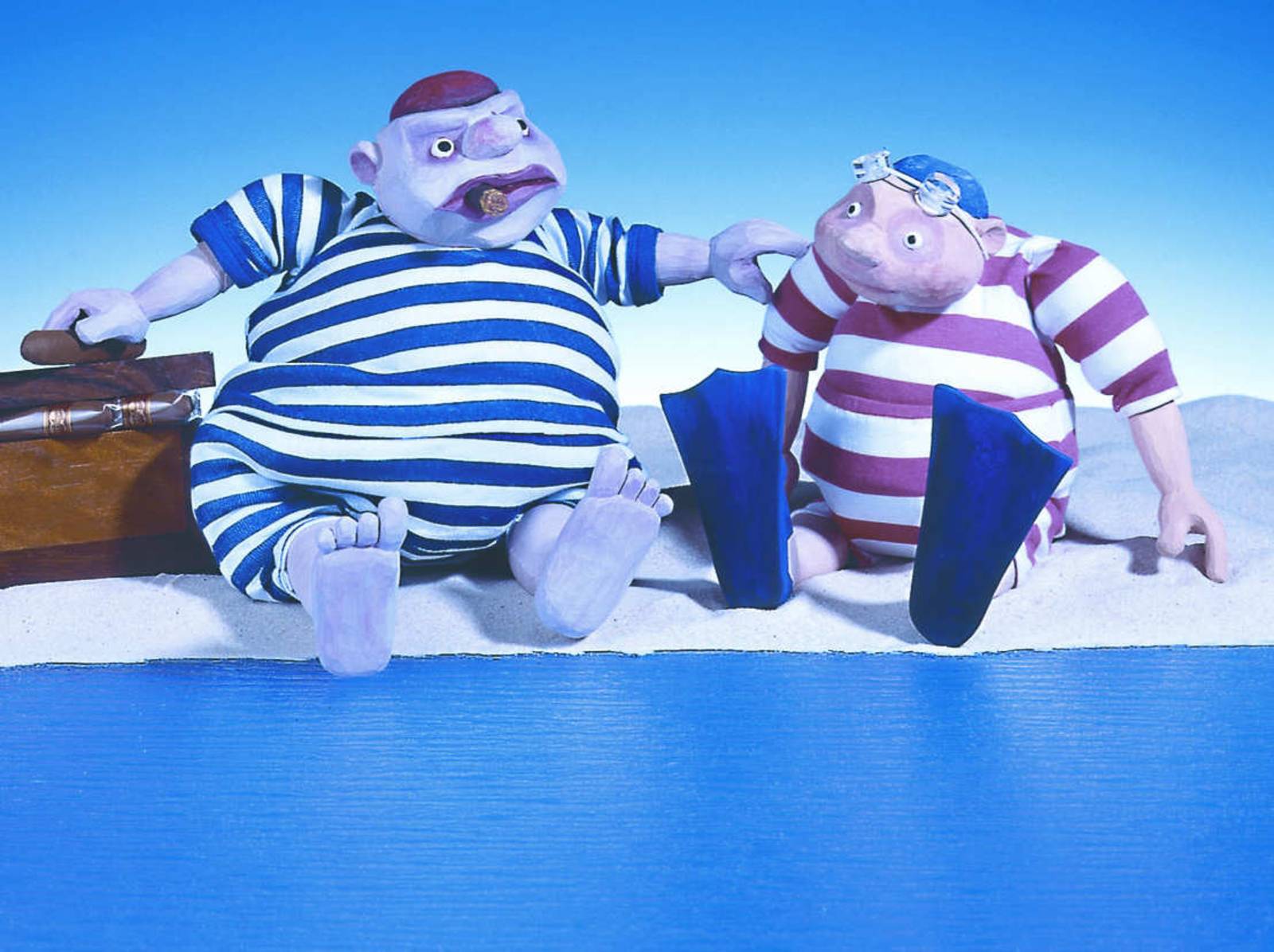 Zwei Figuren des Marmelock-Theaters: Ein dicker Mann im gestreiften Badeanzug mit Zigarre in der Hand und ein dicker Junge, der ebenfalls einen gestreiften Badeanzug trägt.