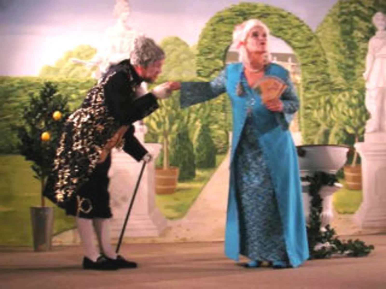 Szene aus einem Theaterstück der nicolaibühne: Ein Mann und eine Frau in Barockkleidern, er verbeugt sich vor ihr und küsst ihr die Hand.