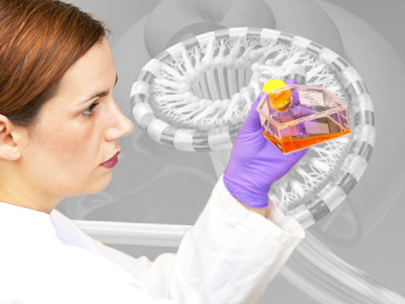 Frau mit weißem Kittel hält durchsichtigen Behälter mit farbiger Flüssigkeit in der Hand