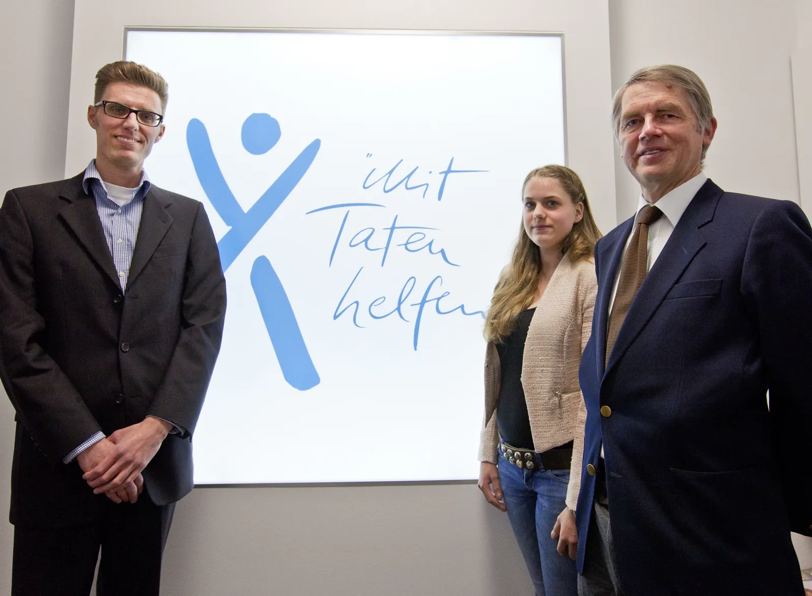 Drei Menschen stehen um einen Schriftzug herum.