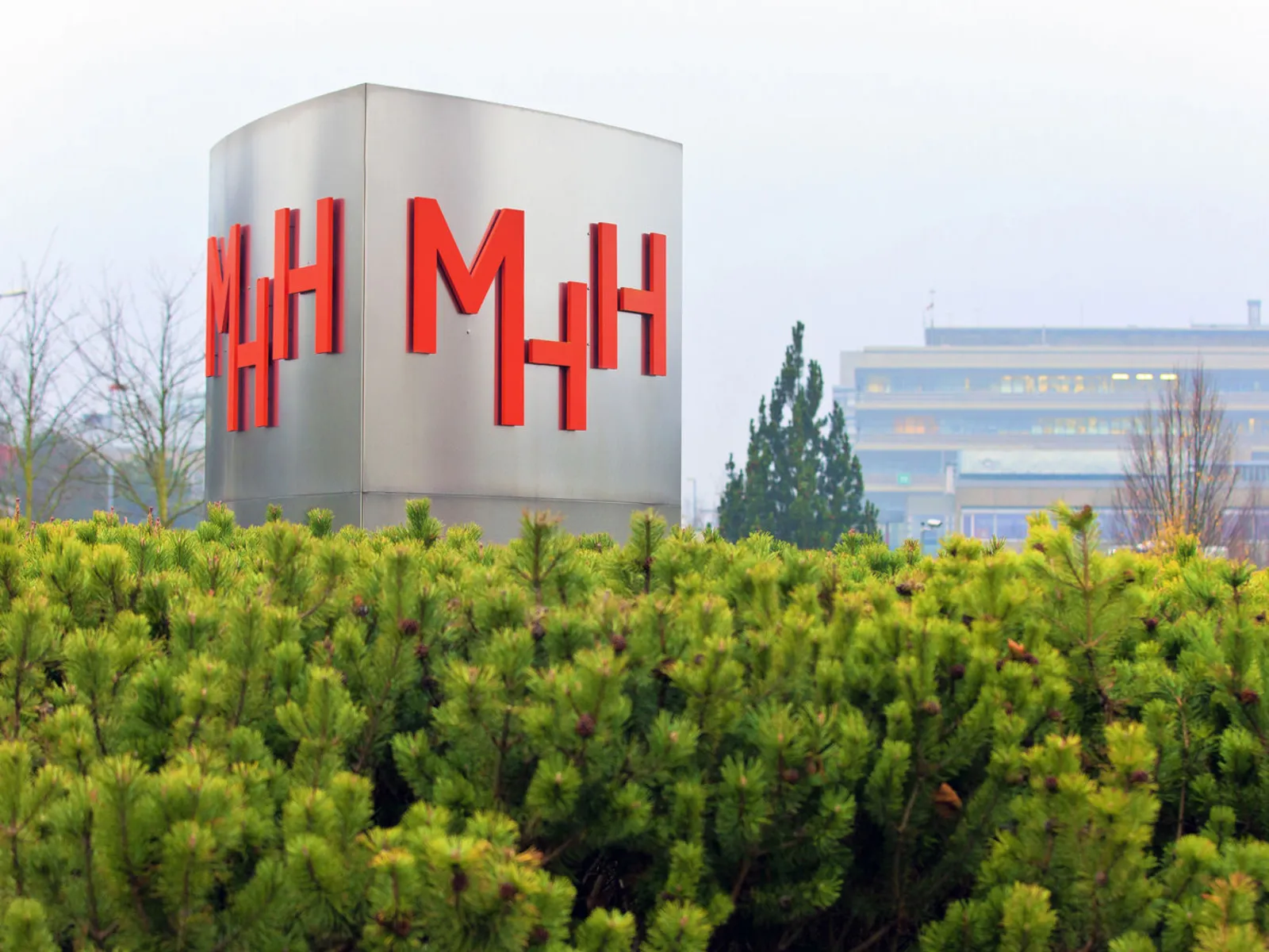 Eine S&auml;ule mit den Buchstaben "MHH", im Hintergrund Geb&auml;ude.