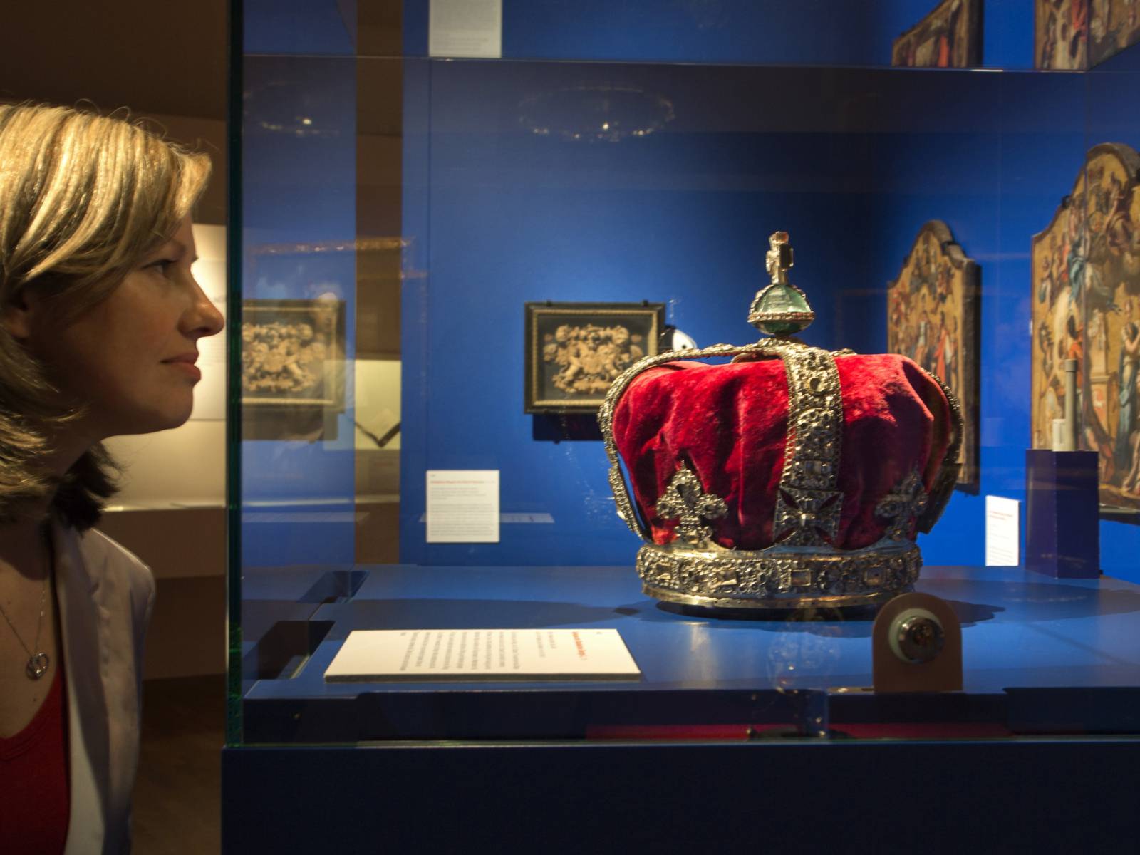 Eine Frau schaut auf eine Krone in einer Ausstellungsvitrine.