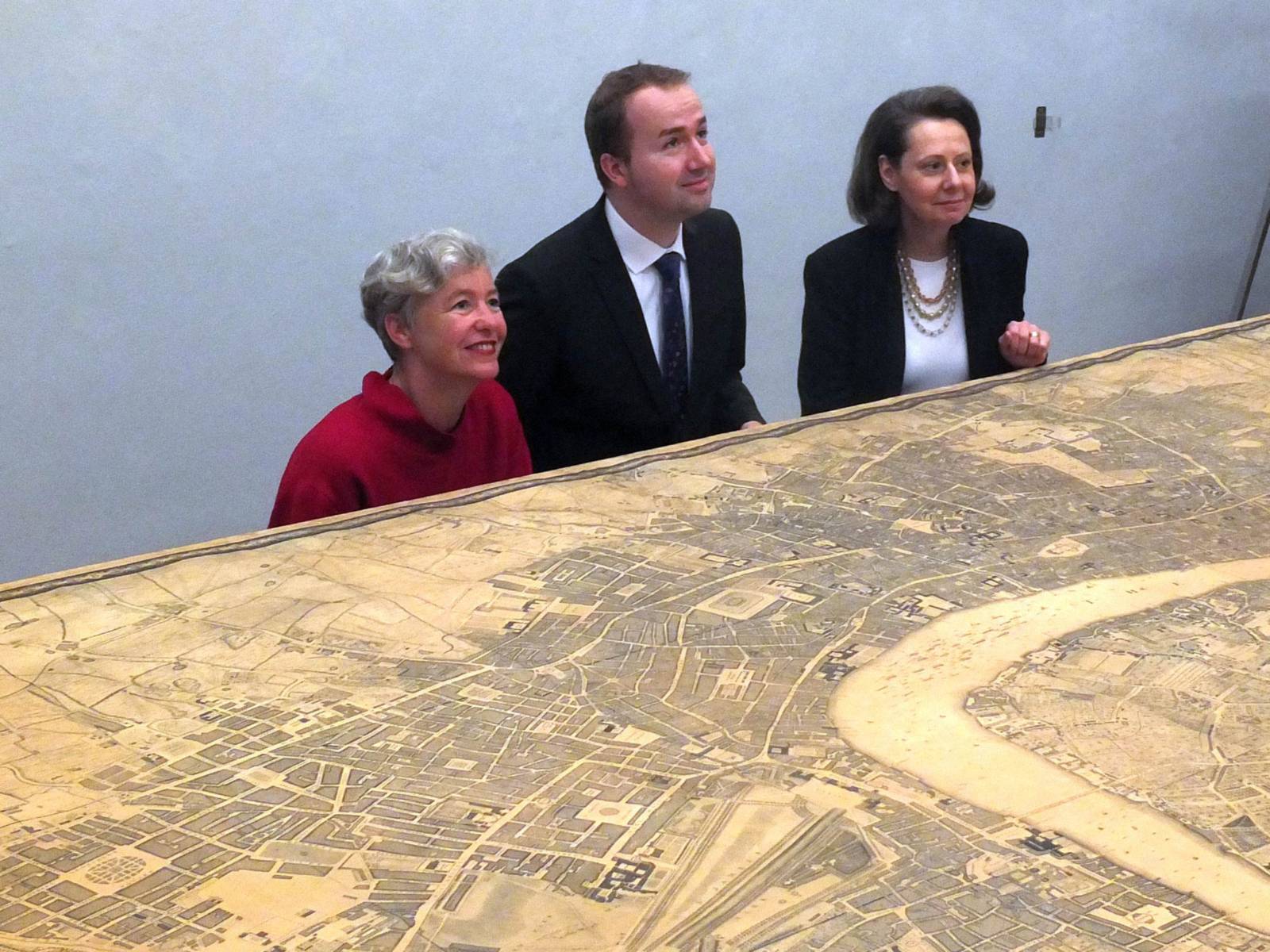 Ein Mann und eine Frau hinter einem 4 Meter breiten historischen Stadtplan von London. 