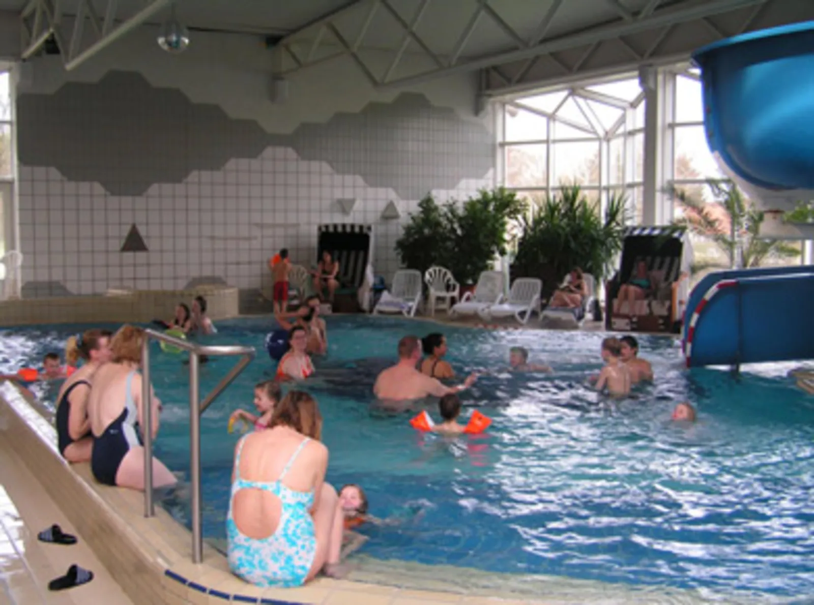 Menschen im Wasser und am Beckenrand in einem Hallenschwimmbad