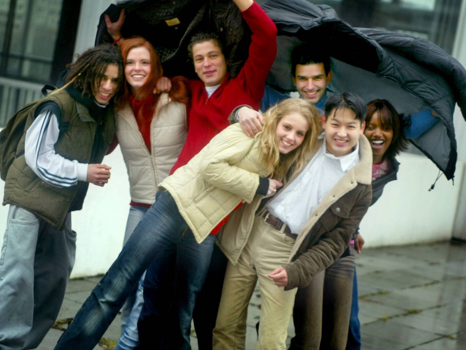 Junge Leute posieren im Regen für ein Gruppenfoto.