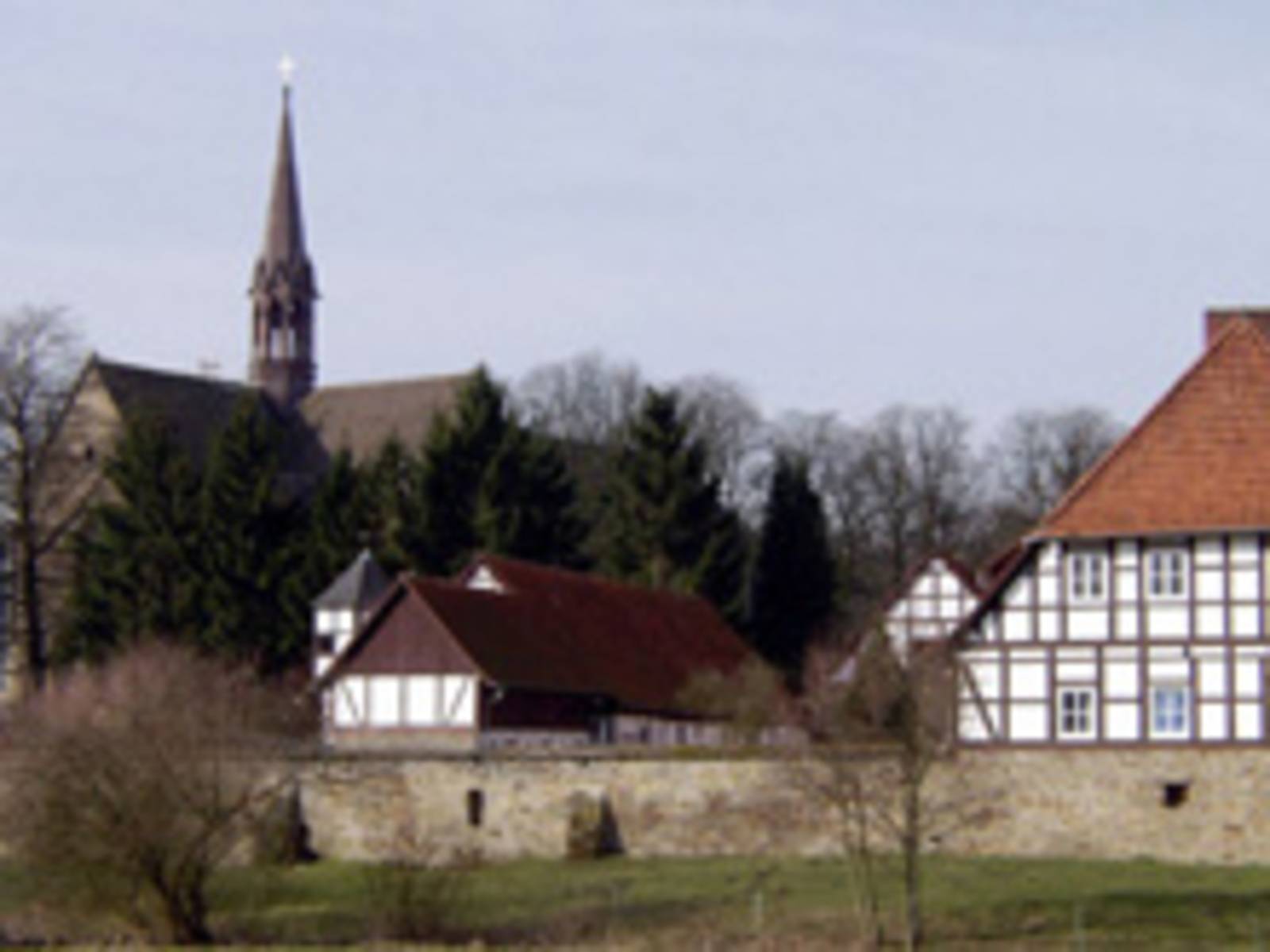 Klostermauer mit dahinterliegenden Fachwerkhäusern und Klosterkirche.