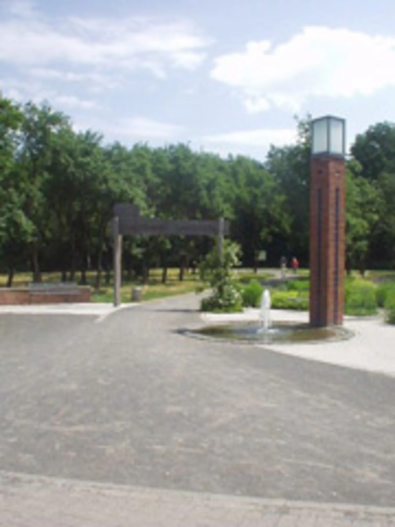 Weg mit gemauerter Lichtstele und einem Holzbogen mit Aufschrift "Stadtpark Garbsen"