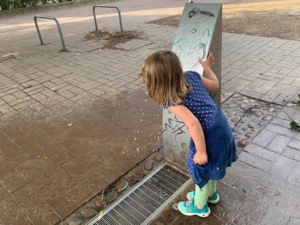 Ein Mädchen, das an einem Brunnen steht.