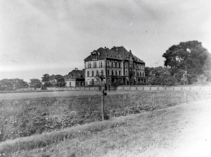 View over the agricultural areas of the Gardening School on the southern side of the girls’ building in 1931, with laundry. Both buildings are surrounded by a wall. 