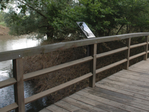 Metalltafel, die am Geländer einer Holzbrücke befestigt ist