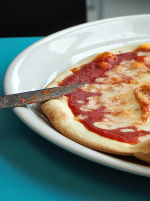 Eine verzehrbereite Pizza liegt auf einem Teller.