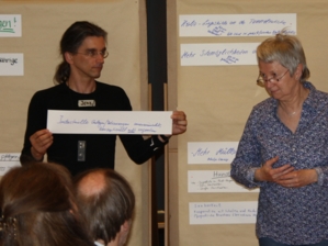 Ein Mann und eine Frau präsentieren Diskussionsergebnisse auf Papierstreifen an einer Pinnwand.