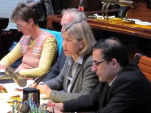 Vier Personen sitzen hinter Pulten. Eine der beiden Frauen spricht.