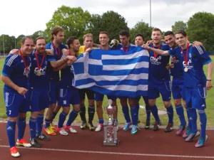 Eine Gruppe junger M&auml;nner in blauen Trikos feiert mit Medaillen um den Hals, einer Griechenland-Flagge und einem Silberpokal auf einer Tartanbahn den Sieg beim Internationalen Hannover Cup 2013