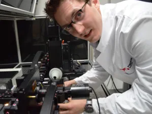 Mann in wei&szlig;em Kittel bedient eine technische Apparatur.