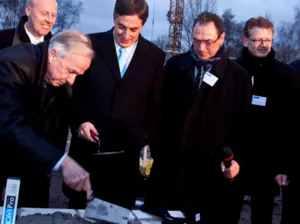 Ein Mann mauert etwas ein, weitere M&auml;nner schauen ihm dabei zu.