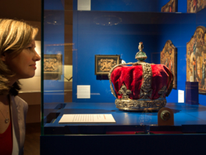 Eine Frau schaut auf eine Krone in einer Ausstellungsvitrine.