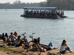 Ein Solarboot und Menschen am Ufer eines Sees.