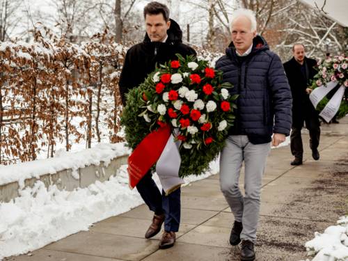 Zwei Männer tragen gemeinsam einen Gedenk-Kranz