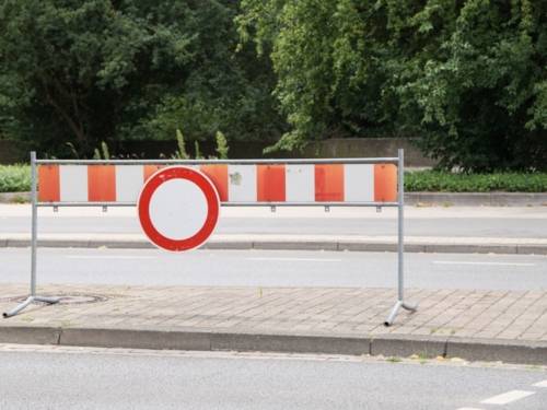 Ein rot-weiß gestreiftes Schild steht quer auf einem Fahrbahn-Mittelstreifen.