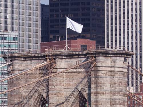 das Bild zeigt einen der Köpfe der Brooklyn Bridge, auf dem eine weiße Fahne weht