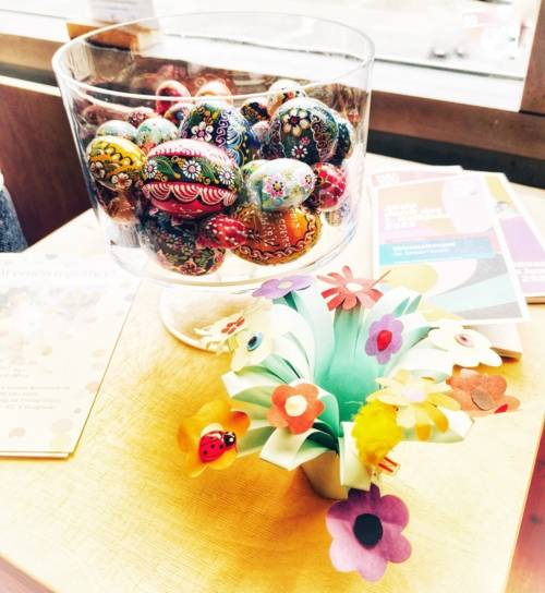 Ein großes Glas mit vielen Ostereiern und ein Blumenstrauß aus Papier.