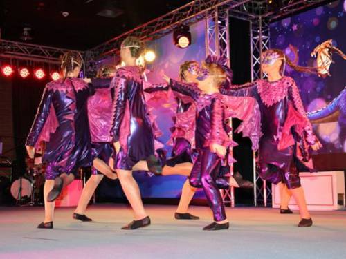 Verkleidete Kinder tanzen auf einer Bühne im Kreis.