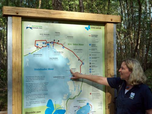 Eine Frau steht an einer Tafel mit einer Karte und zeigt auf einen Punkt am Steinhuder Meer.
