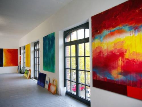 Blick in das Atelier einer Künstlerin: Kunstwerke hängen oder lehnen an einer Wand.