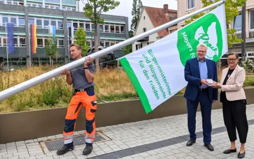 Oberbürgermeister Thomas Ebersberger und Künstlerin Lucie Kazda beim Hissen der Flagge Mayors for Peace