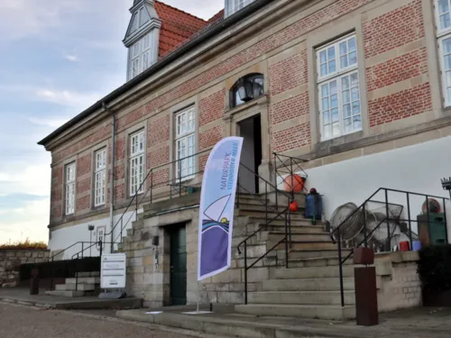 Blick auf Schloss Landestrost, davor steht eine Strandflagge des Naturparks Steinhuder Meer.