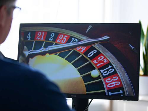 Ein Mann sitzt vor einem Bildschirm und spielt online Roulette.