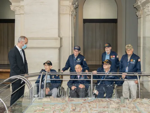Oberbürgermeister Onay steht mit sechs US-Veteranen an einem Stadtmodell Hannovers.