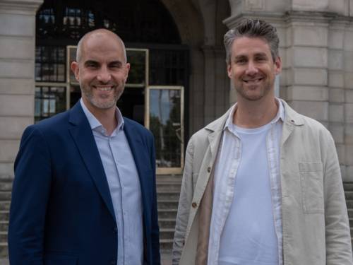 Zwei Personen stehen nebeneinander und schauen in die Kamera.