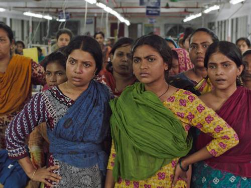 Farbenfroh gekleidete Indonesierinnen stehen in einer Textilfabrik beieinander.