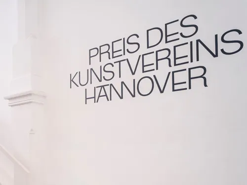 Das Foto zeigt eine weiße Wand in den Räumlichkeiten des Kunstvereins Hannover, auf der der Schriftzug „Preis des Kunstvereins Hannover“ steht.