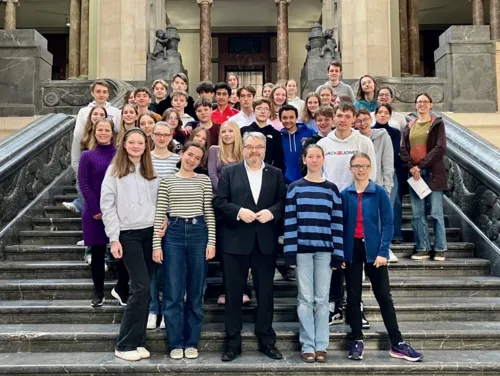 Schüler*innen der Sophienschule Hannover und der Institution Jean-Paul II. aus Rouen stehen auf der Rathaustreppe des Neuen Rathauses Hannover, gemeinsam mit dem Bürgermeister der Landeshauptstadt Hannover Thomas Hermann.