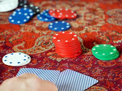 Poker-Chips und Spielkarten liegen auf einem Spieltisch mit rotem Bezug.
