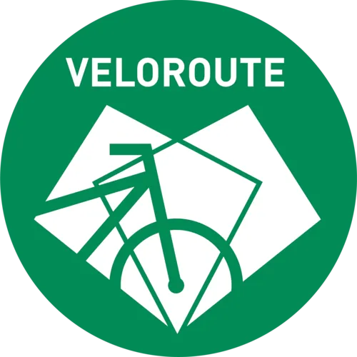 Ein grünes, rundes Logo. In den kreisrunden Logo ist ein weißes Fahrrad abgebildet und die Aufschrift Veloroute zu lesen.