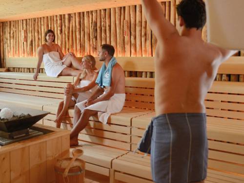 Erwachsene in einer Sauna, eine Person schwenkt ein Handtuch