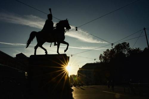 Die Silhouette einer Statue eines Reiters. Neben dem Sockel der Statue scheint ein Sonnenstrahl.