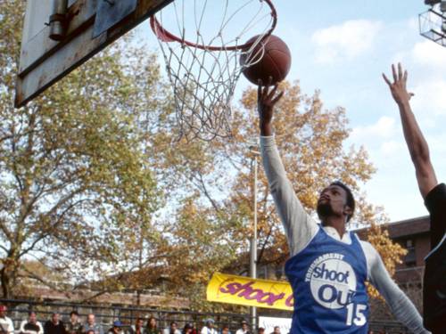 ein Mann wirft einen Ball in ein Basketballnetz