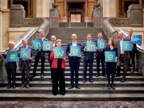 Menschen stehen auf einer großen Treppe und halten Tafeln in den Händen, die den Begriff #knowember bilden.