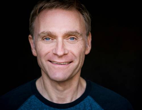 Nahporträt eines lächelnden Mannes mit kurzem Haar und buschigen Augenbrauen