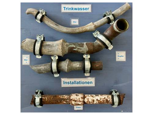 Diverse Rohrabschnitte mit Bleirohren auf einer Schautafel