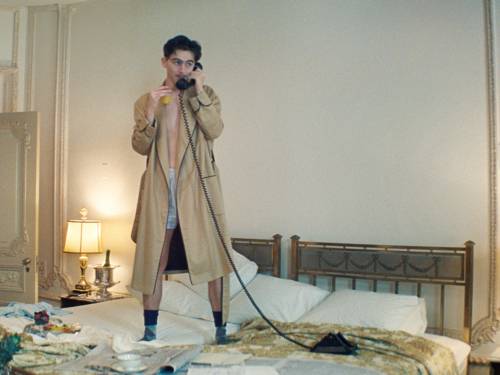 Ein Mann steht auf einem Bett und telefoniert