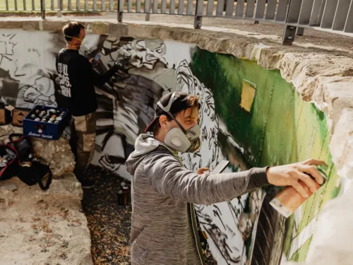 Ein Mann sprüht an einem Graffitto